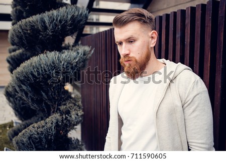 young guy with a beard and mustache posing on the street in the sunlight, fashion man, style, vintage style, retro men, handsome beard, outdoor portrait, hipster man