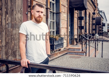 young guy with a beard and mustache posing on the street in the sunlight, fashion man, style, vintage style, retro men, handsome beard, outdoor portrait, hipster man