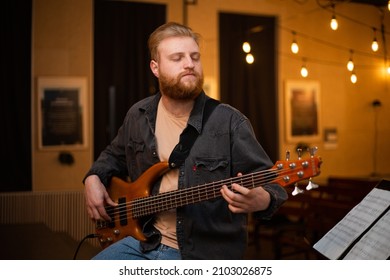 A Young Guy With A Beard Plays A Bass Guitar With Five Strings