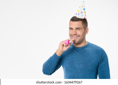 Young Guy In Birthday Hat And Party Pipe Posing Isolated On White Background