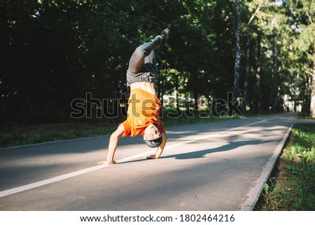 Young guy breakdancer dancing on the road in the park in summertime. Breakdancing school poster