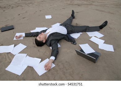 Young Guy In A Business Suit Is On The Beach Among The Scattered Papers