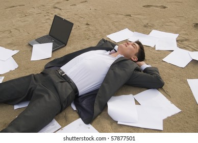 Young Guy In A Business Suit Is On The Beach Among The Scattered Papers