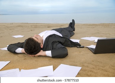 young guy in a business suit is on the beach among the scattered papers - Powered by Shutterstock