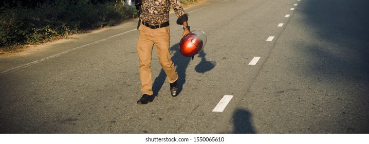 Young Guy Carrying A Red Bike Helmet Walking In A Streets