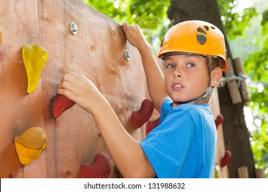 Young guy with  climbed equipment on the top of climbing wall.