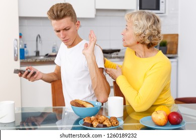 Young Guy Concentrated Using His Smartphone And Not Paying Attention To Mom