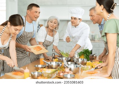 Young guy cook at master class teaches group of people how to cook food