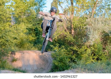 young guy cyclist does jumps and tricks on a bike. in the forest against the setting sun - Powered by Shutterstock