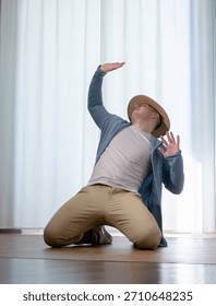 Young guy dancer in motion in a pose. A man performs a modern dance in casual clothes.