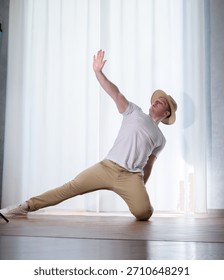Young guy dancer in motion in a pose. A man performs a modern dance in casual clothes.