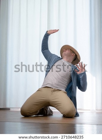 Young guy dancer in motion in a pose. A man performs a modern dance in casual clothes.