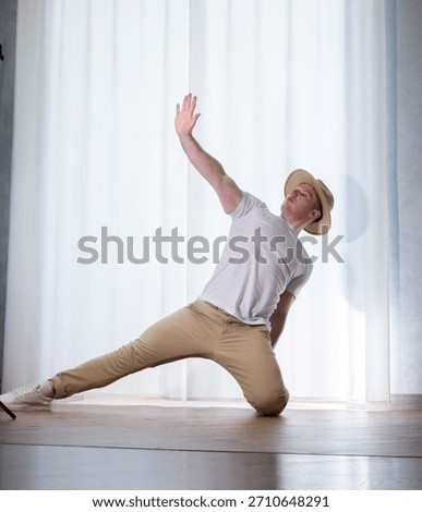 Young guy dancer in motion in a pose. A man performs a modern dance in casual clothes.
