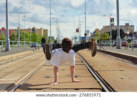Young guy dancing breakdance on tramlines in the city