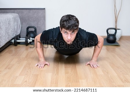 Young guy doing push-ups from the floor at home, doing morning exercises before studying at college, getting energy for the whole day. The guy is exercising at home, sport concept