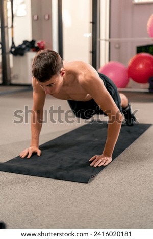 young guy doing push-ups on the mat in the gym doing exercises for the muscles of arms