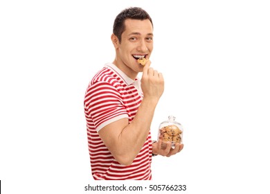 Young guy eating a cookie and holding a cookie jar isolated on white background