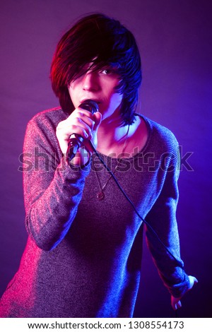 The young guy in emo style is singing in microphone.