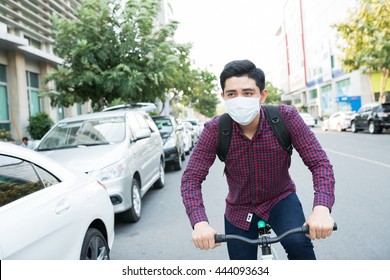 Young guy in face mask riding bike in the street - Powered by Shutterstock