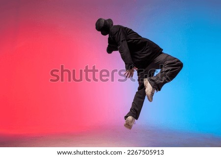 young guy falls upside down in the air, man levitates and flies down in neon lighting, acrobat dancer flies in a jump, concept of dreams and fantasies