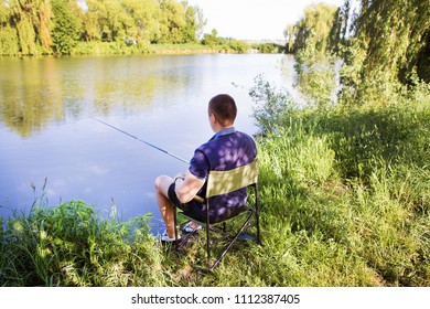 young guy fishing on a lake sitting in a chair - Shutterstock ID 1112387405