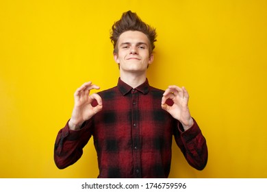 Young Guy With Funny Hairstyle Shows Okay On Yellow Isolated Background, Man With Strong Hair Styling, Copy Space