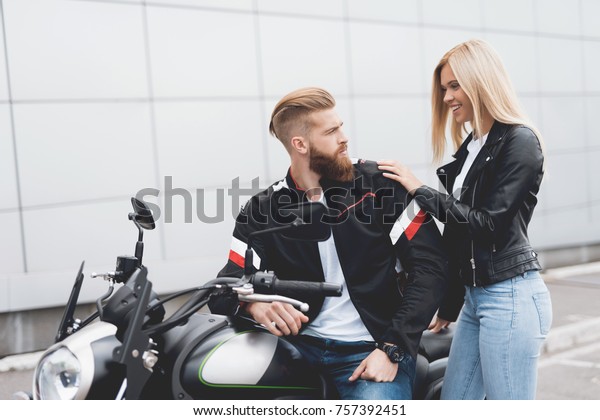 Young guy\
and girl sitting on a modern electric motorcycle. They are in love.\
They prepare to leave together to\
travel.