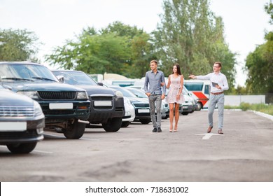 A young guy with a girl walks in the parking lot and chooses a car.