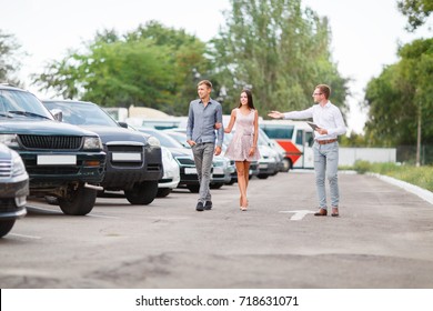 A young guy with a girl walks in the parking lot and chooses a car.