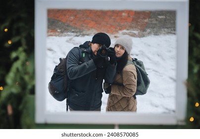A young guy and a girl in winter clothes are photographed with a SLR camera in the mirror. Self-portrait of a loving couple. Lviv, Ukraine.