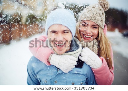 Young guy and girl in winterwear enjoying snowfall