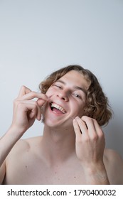 A Young Guy With Long Hair Flossing His Teeth. Oral Care.