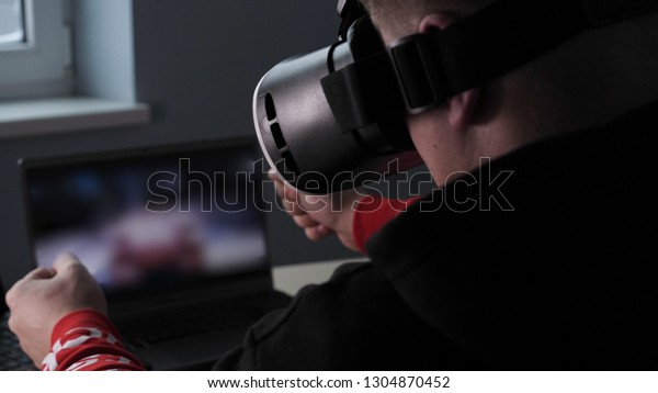 Young guy (male) player in virtual glasses plays\
(relaxes) against him 2 game monitors, he moves his hands seeing\
the movement with glasses. Concept of: Lifestyle, Underworld, 3d,\
Virtual reality