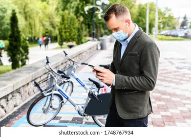 A Young Guy With Medical Mask In Smart Casual Wear Going To Rent City Bike. The Guy Gets To Work Without Using Public Transport