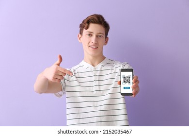 Young guy pointing at smartphone with QR code on screen against lilac background