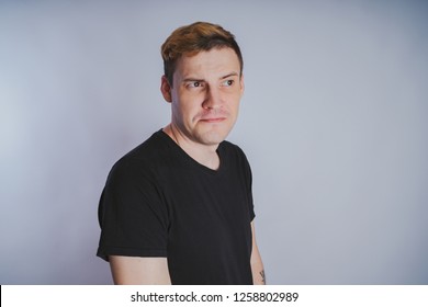 Young guy with posing in the Studio. Short hair and clean skin. Emotional portrait. Street style clothing: black t-shirt and jeans
