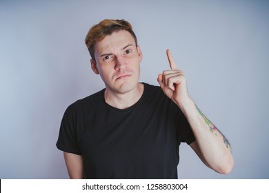 Young guy with posing in the Studio. Short hair and clean skin. Emotional portrait. Street style clothing: black t-shirt and jeans
