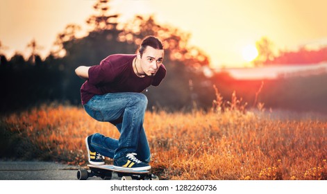 Young guy riding a skateboard in the golden hour time.
