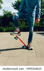 Young Guy In Ripped Jeans Standing With Penny Board In The Park. Summer Activities Skateboarding