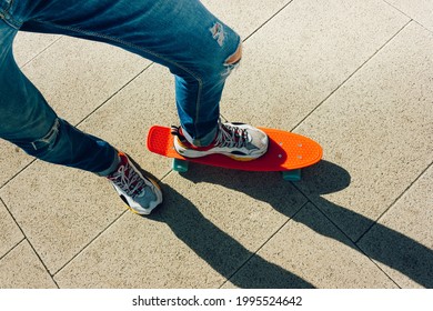 Young Guy In Ripped Jeans Standing With Penny Board In The Park. Summer Activities Skateboarding