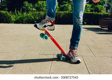 Young Guy In Ripped Jeans Standing With Penny Board In The Park. Summer Activities Skateboarding.