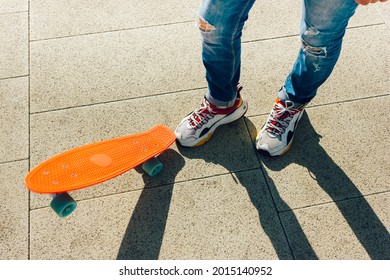 Young Guy In Ripped Jeans Standing With Penny Board In The Park. Summer Activities Skateboarding