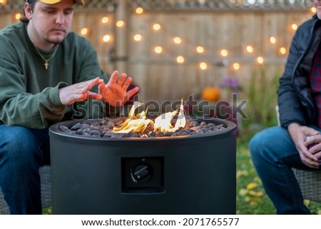 Young guy sitting by a fire in the backyard