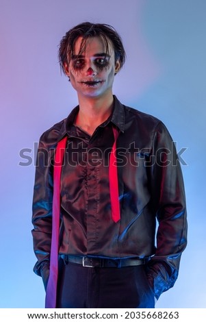 The young guy with skull makeup celebrating a Halloween party or Mexican Day of the Dead. A gothic-punk man with a face painted in the make-up of a dark clown, cosplay joker, wizard, vampire, devil Stock photo © 