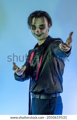The young guy with skull makeup celebrating a Halloween party or Mexican Day of the Dead. A gothic-punk man with a face painted in the make-up of a dark clown, cosplay joker, wizard, vampire, devil Stock photo © 