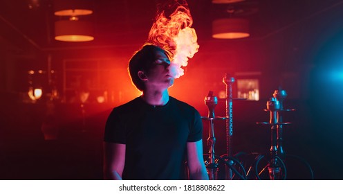 Young Guy Smokes A Shisha And Lets Out A Cloud Of Smoke In The Hookah Room