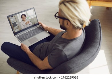 Young Guy Speaking With Online Doctor On Laptop At Home. Male Patient Consulting Healthcare Provider On Webcam