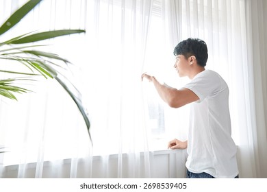 Young guy standing at the front of window with bright sunlight. 171