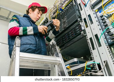 A Young Guy Standing On The Stairs Measures The Signal Level In A Fiber Optic Cable. The Technician Checks The Quality Of The Internet Connection In The Server Room Of The Data Center.