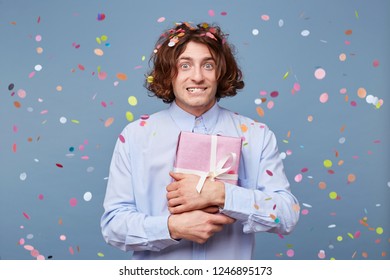 A Young Guy Stands Holding A Gift Box Expression On His Face Confused Puzzled And Bit His Lower Lip As If Something Had Forgotten Or Did Not Come Up With A Greeting For The Birthday Boy.